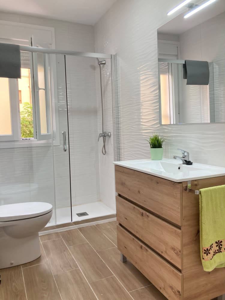 Baño 2 con ducha, ventana y lavabo sobre mueble de madera