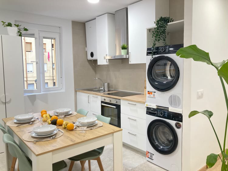 Cocina equipada con horno, placa, lavadora, secadora y mesa de comedor