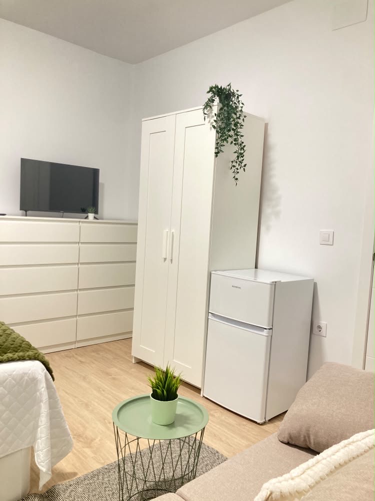 Habitación B: armario blanco, televisión, mini frigorífico y sofá